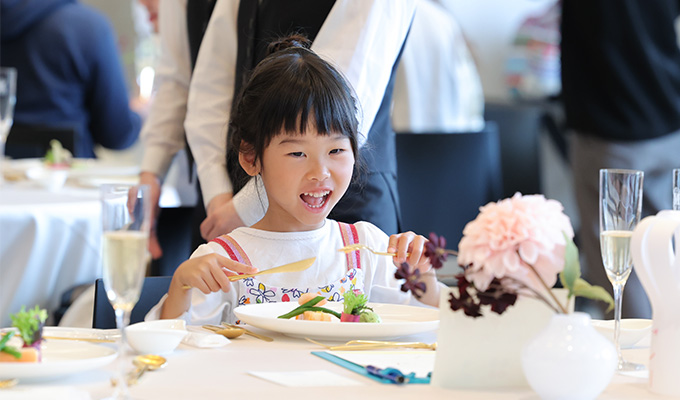 ナイフとフォークを使って料理を食べる子どもたち